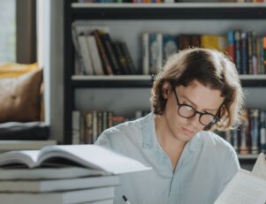 estudante pesquisa sobre bolsas de estudo em diferentes livros