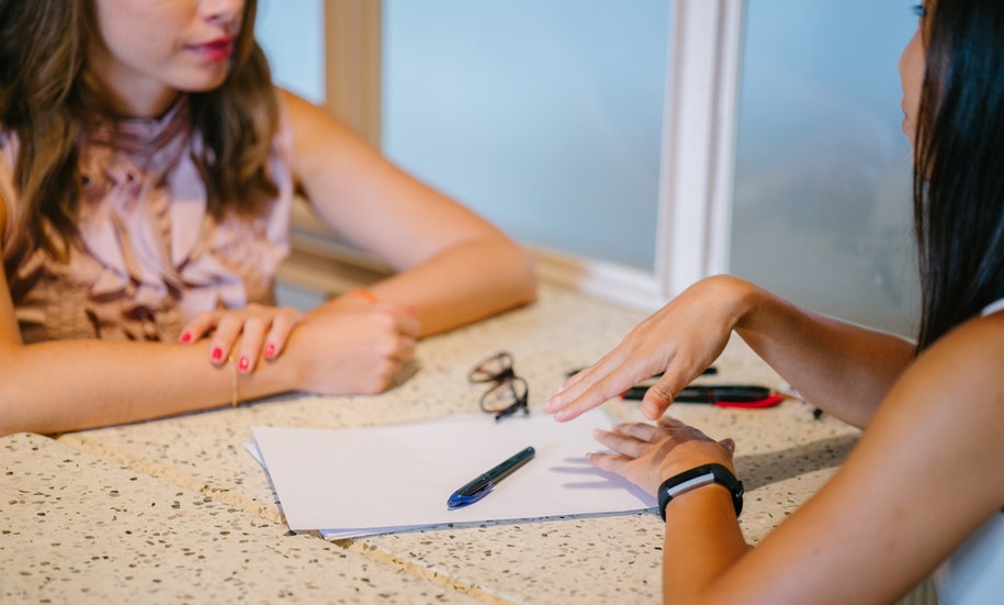 Duas mulheres sentadas uma de frente para a outra conversando