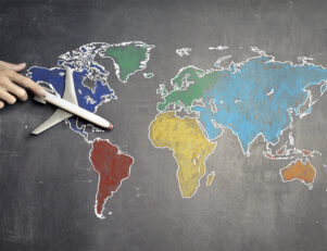 Mapa mundi, com países em cores diferentes e uma mão segurando um avião de brinquedo