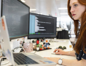 Mulher ruiva sentada em frente a um computador em um escritório