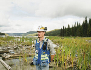 Homem com capacete e colete o meio de um campo com água