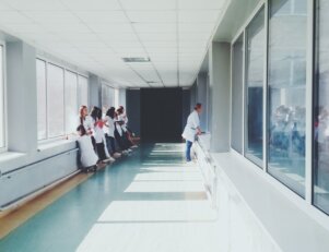 Corredor de um hospital com pessoas usando jaleco branco no fundo
